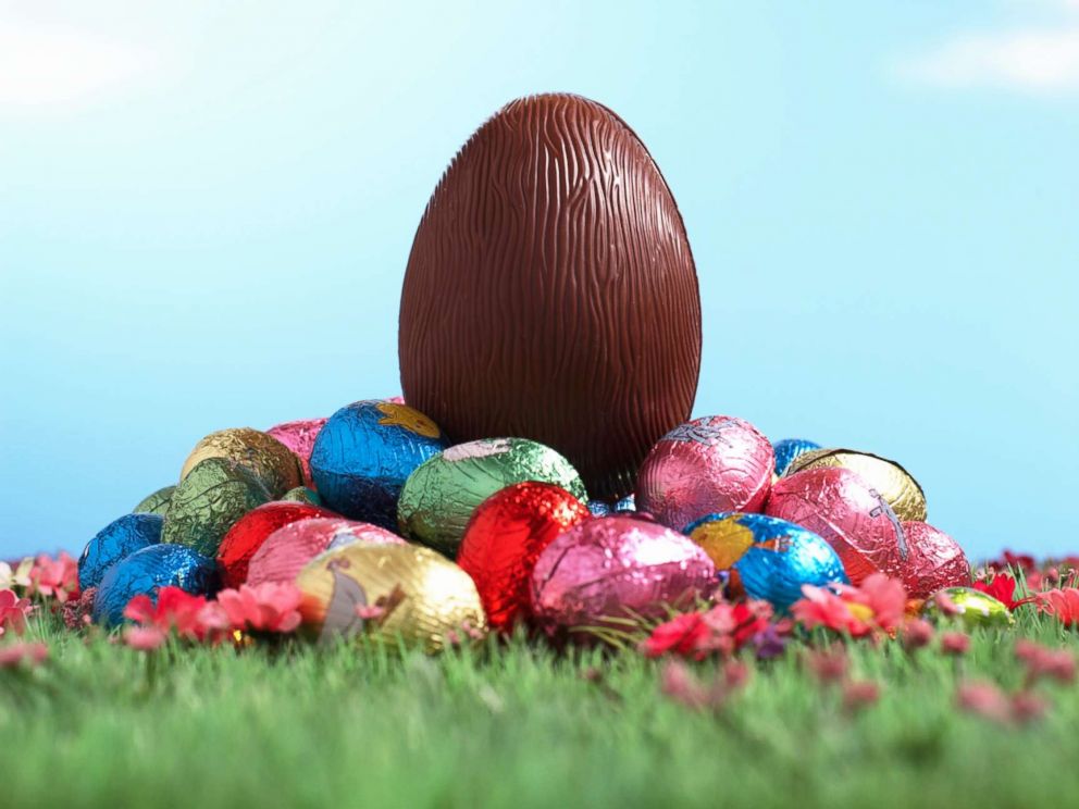 PHOTO: A chocolate egg sits on pile of foil wrapped Easter eggs on grass.
