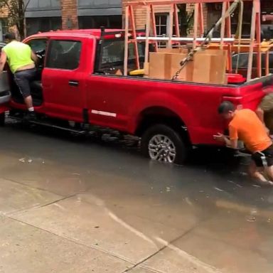 A submerged pickup truck was pushed through floodwaters in Hoboken after Tropical Storm Fay hit the area.