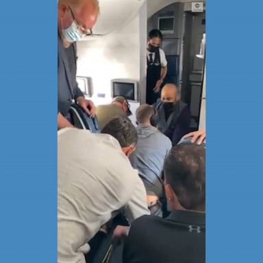 A dramatic video shows passengers and crew subduing a man who allegedly attempted to break into the cockpit of a Delta flight.