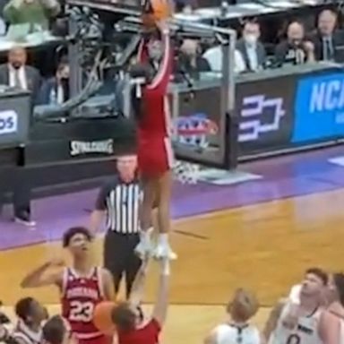 After players and the referee at a March Madness game failed to retrieve a basketball wedged behind a backboard, two cheerleaders stepped in to help and the crowd went wild.