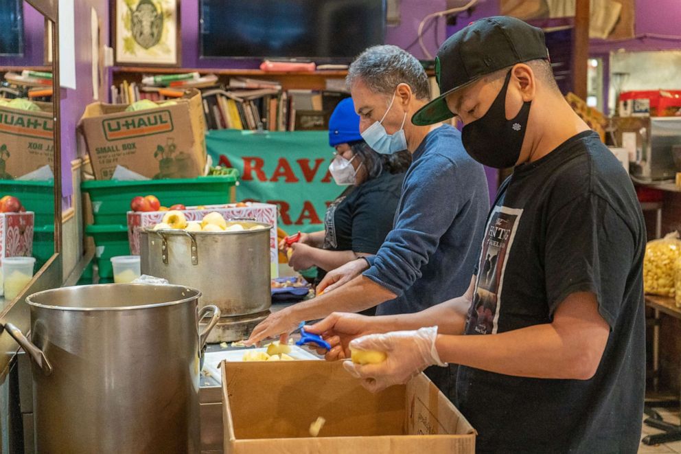 PHOTO: Volunteers J.J. Kingsman, front, Leo Alexandropoulos, middle, with Yajaira Saavedra, Mutual Aid Coordinator for La Morada, preparing applesauce that will feed about 450 people.