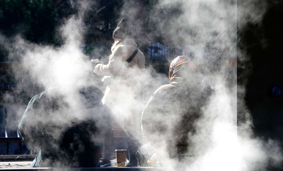 PHOTO: People sit by a steam pipe as they brave the temperatures in Central Park in New York City on Jan. 11, 2022.