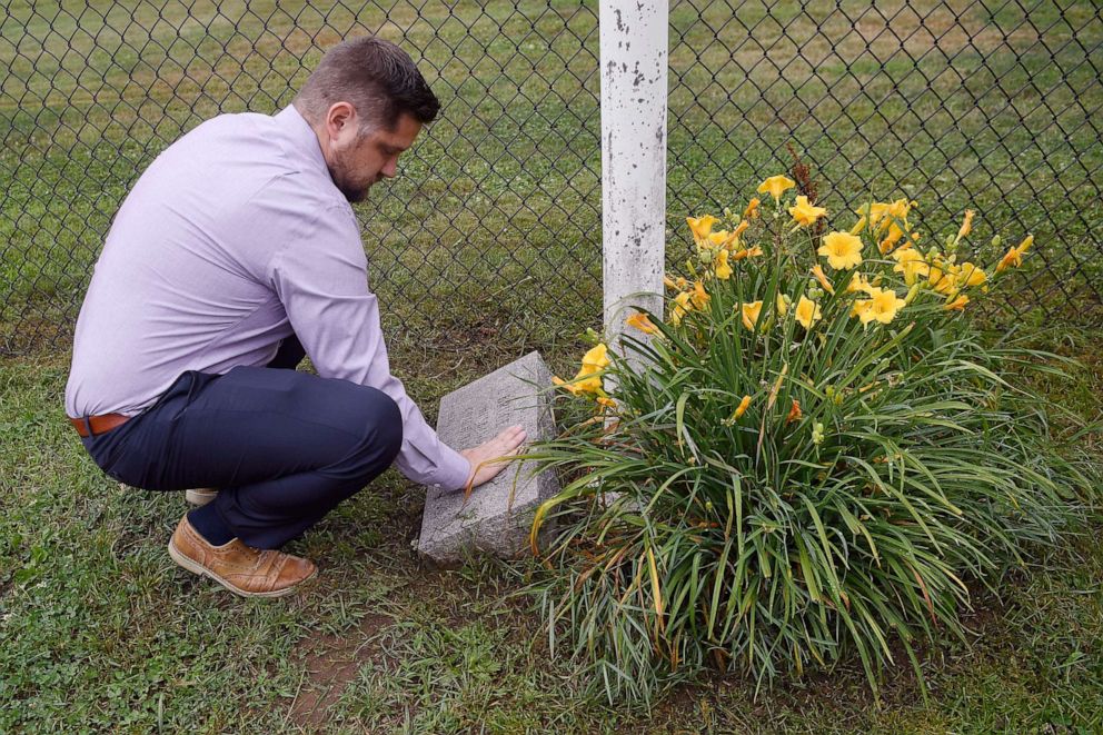 PHOTO: Brett Eagleson, son of Sept. 11th victim Bruce Eagleson, wipes grass off a memorial stone for his father at the baseball field where his father use to coach, July 2, 2021, in Middletown, Conn.