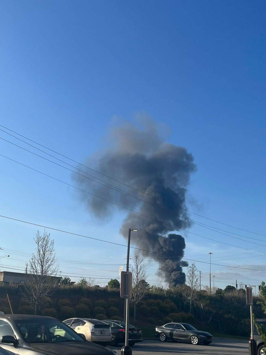 PHOTO: Smoke is seen after a small plane crashed in the lot of a General Mills plant in Covington, Georgia, on April 21, 2022.