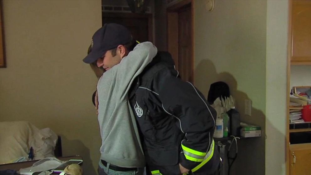 PHOTO: Firefighter Ryan McCuen is hugged by a member of the Stone family. McCuen paid their electric bill after he responded to a call and found that their 18 year old son, Troy, was not able to use his ventilator because power had been cut off.