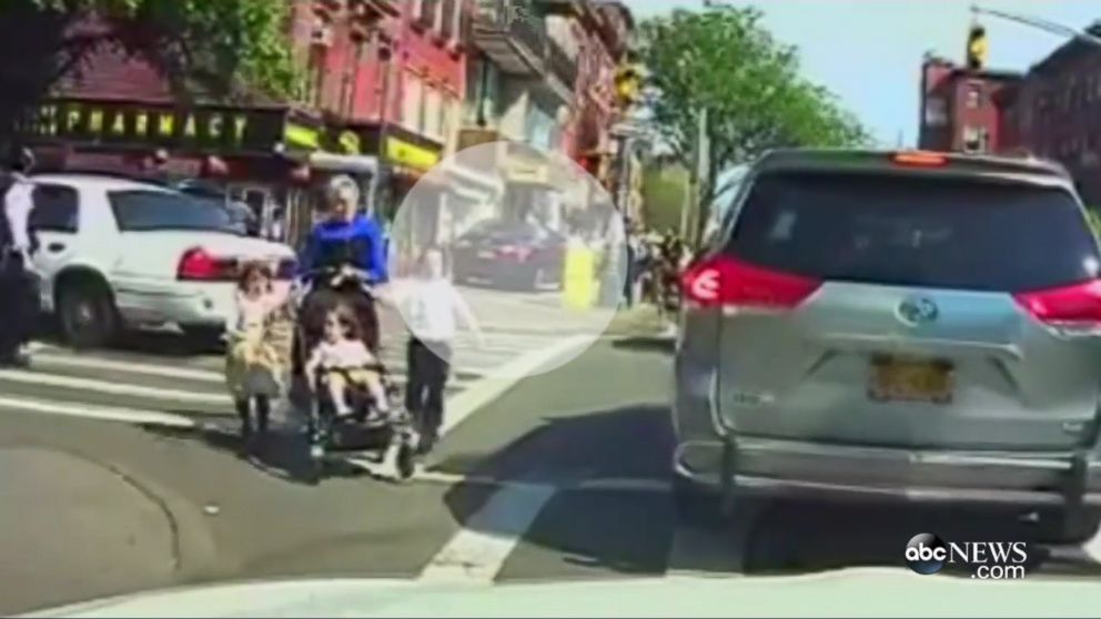 PHOTO: A woman with a stroller and three small children dash across a busy intersection to avoid the black car speeding down the sidewalk behind them, May 26, 2016, in Brooklyn, New York.