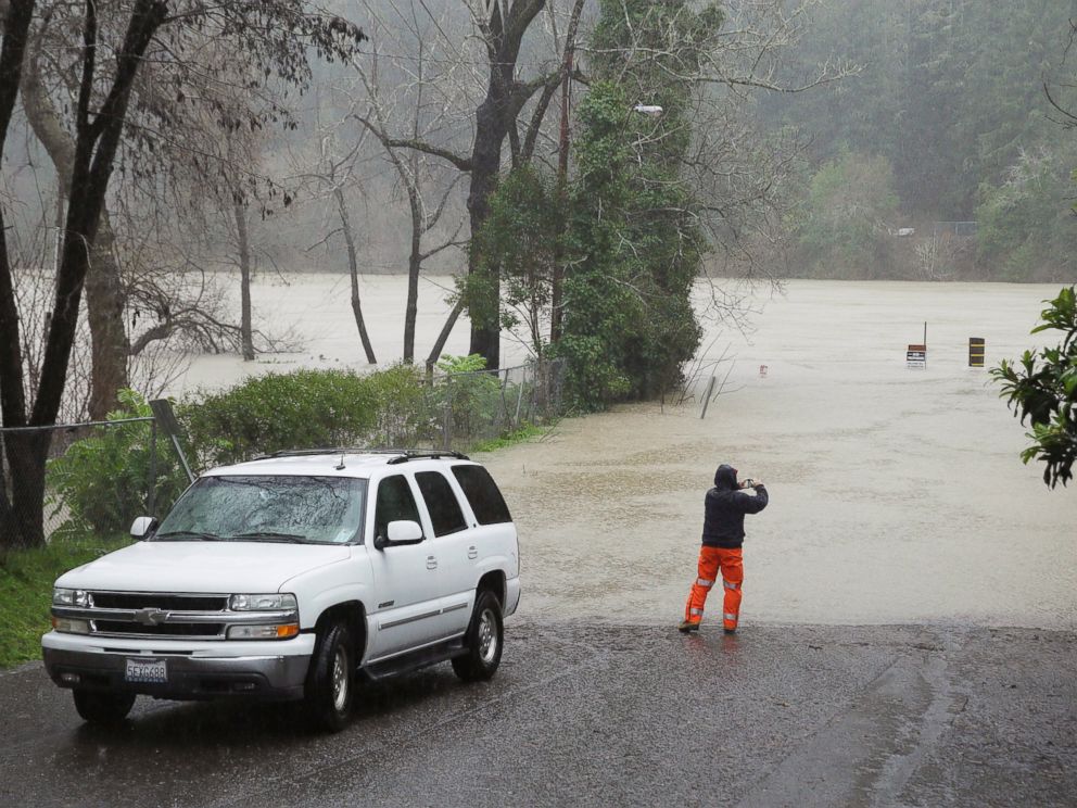PHOTO: A man stops to take a picture of the Russian River as it floods Johnsons Beach, Jan. 10, 2017, in Guerneville, California.
