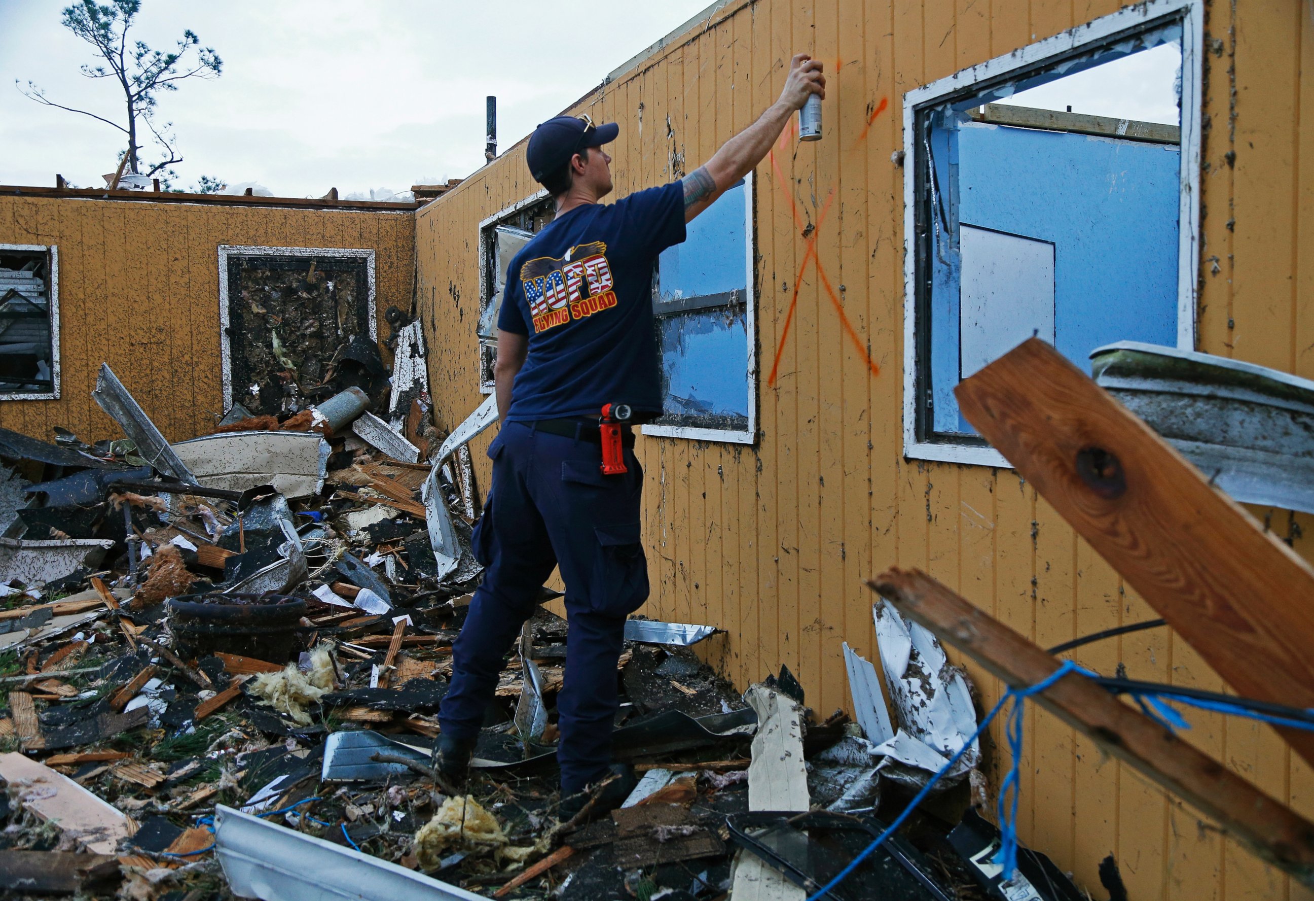 PHOTO: New Orleans Firefighter Jared Carter spray paints a search signal after conducting a secondary search of homes damaged by a tornado that touched down yesterday in eastern New Orleans, Feb. 8, 2017.  