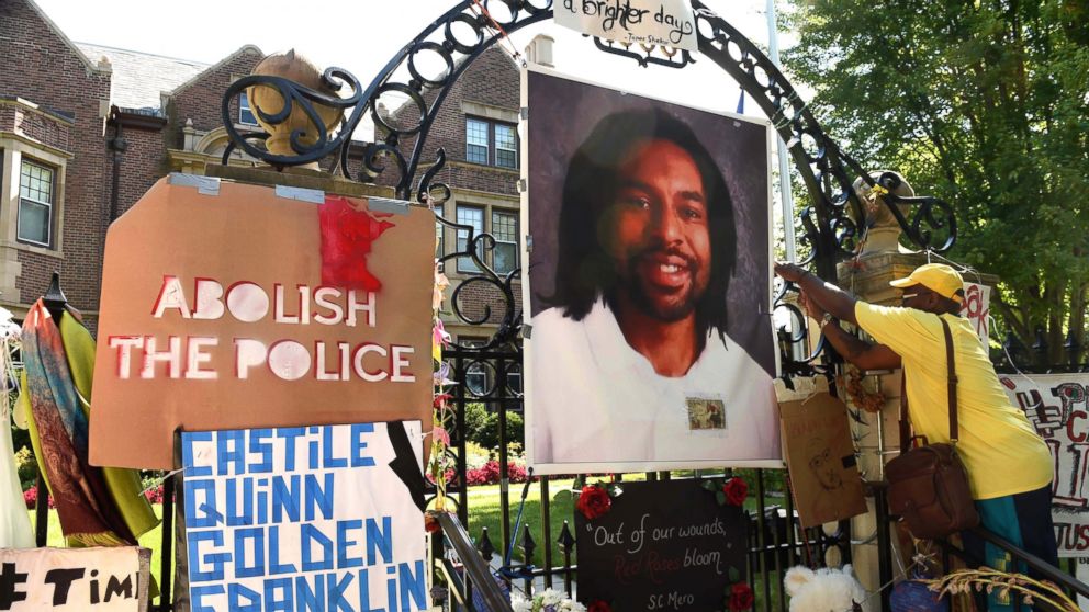 King Demetrius Pendleton hangs a sign on the gate of the Governor's Residence in St. Paul, Minn., as protesters demonstrate against the July 6 shooting death of Philando Castile by a St. Anthony police officer making a traffic stop in Falcon Heights, Michigan, July 24, 2016 .