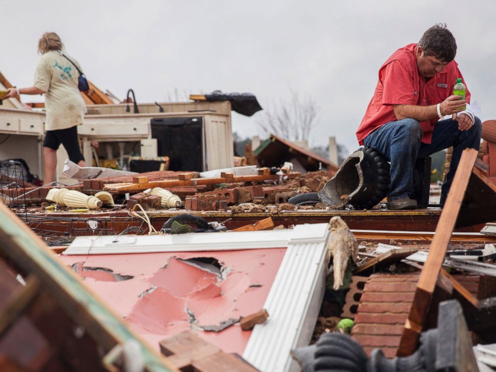 PHOTO: Jeff Bullard sits in what used to be the foyer of his home as his daughter, Jenny Bullard, looks through debris at their home that was damaged by a tornado, Jan. 22, 2017, in Adel, Georgia.