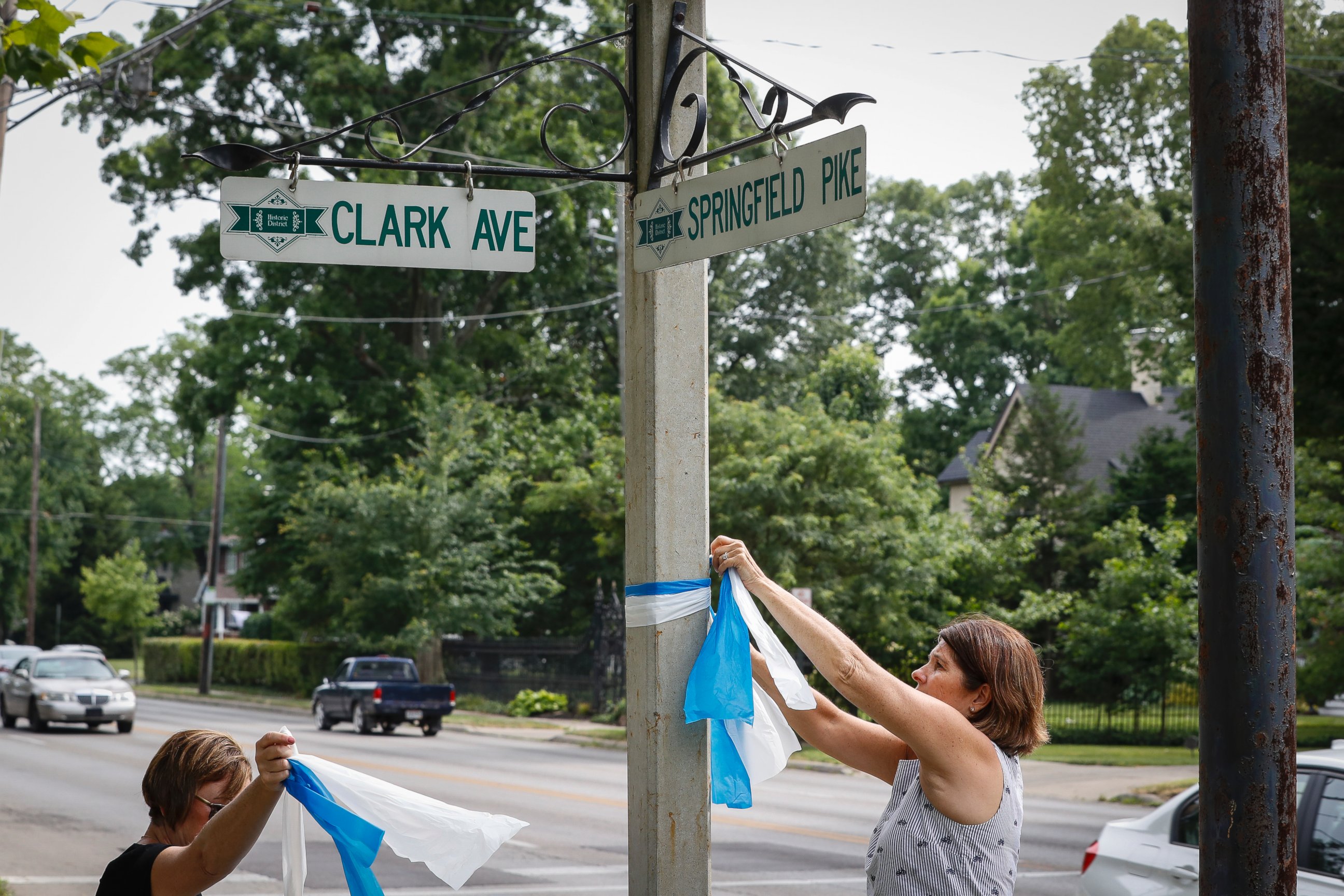 PHOTO: Denise Koesterman, right, and Alison Lebrun, left, tie blue-and-white awareness ribbons along Springfield Pike near the family home of Otto Warmbier, June 13, 2017. 