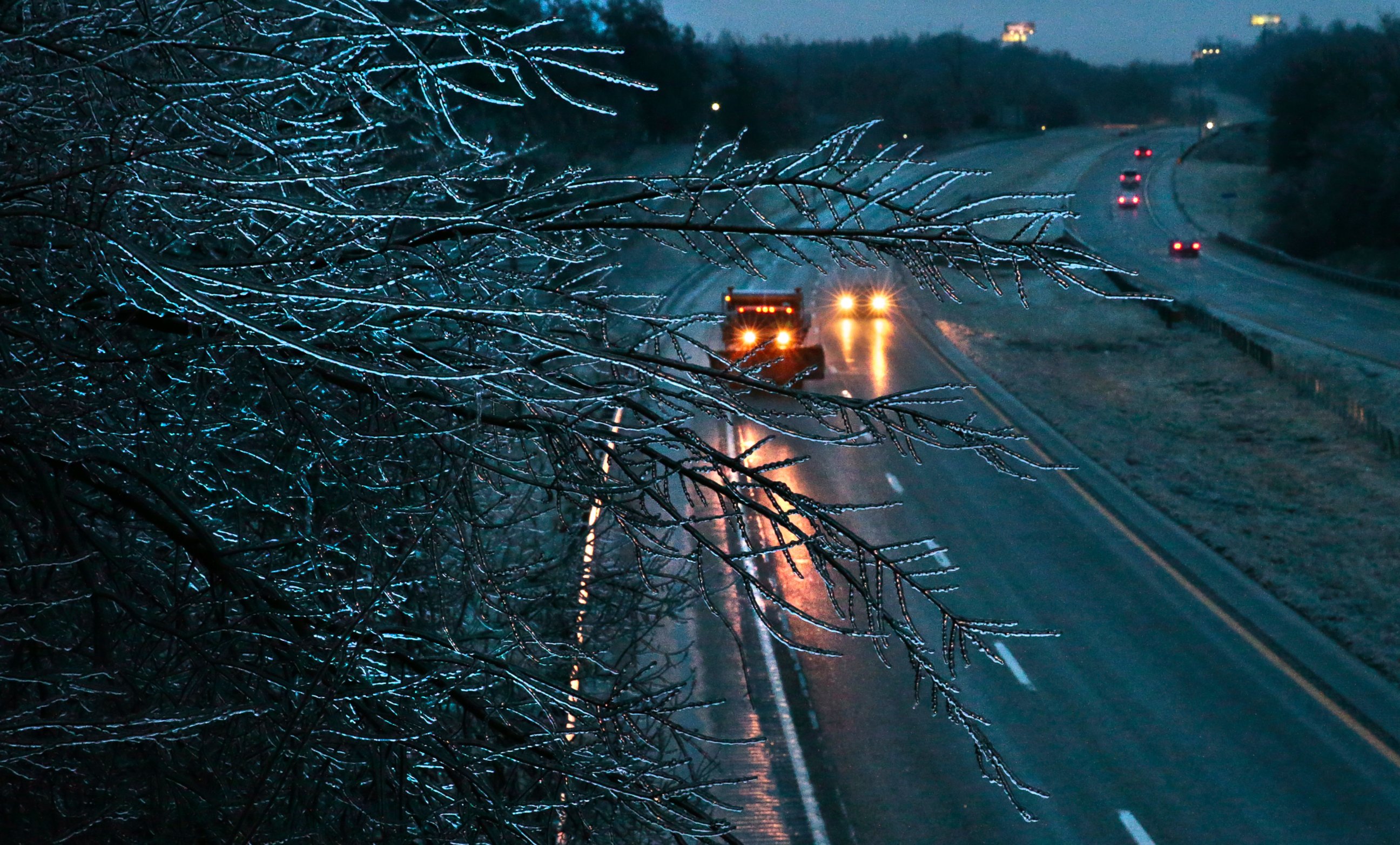 PHOTO: A Missouri Department of Transportation salt truck spreads ice melt on Interstate 55 as coated tree branches sway overhead as seen from the Main Street bridge, Jan. 13, 2017 in Festus, Missouri. 