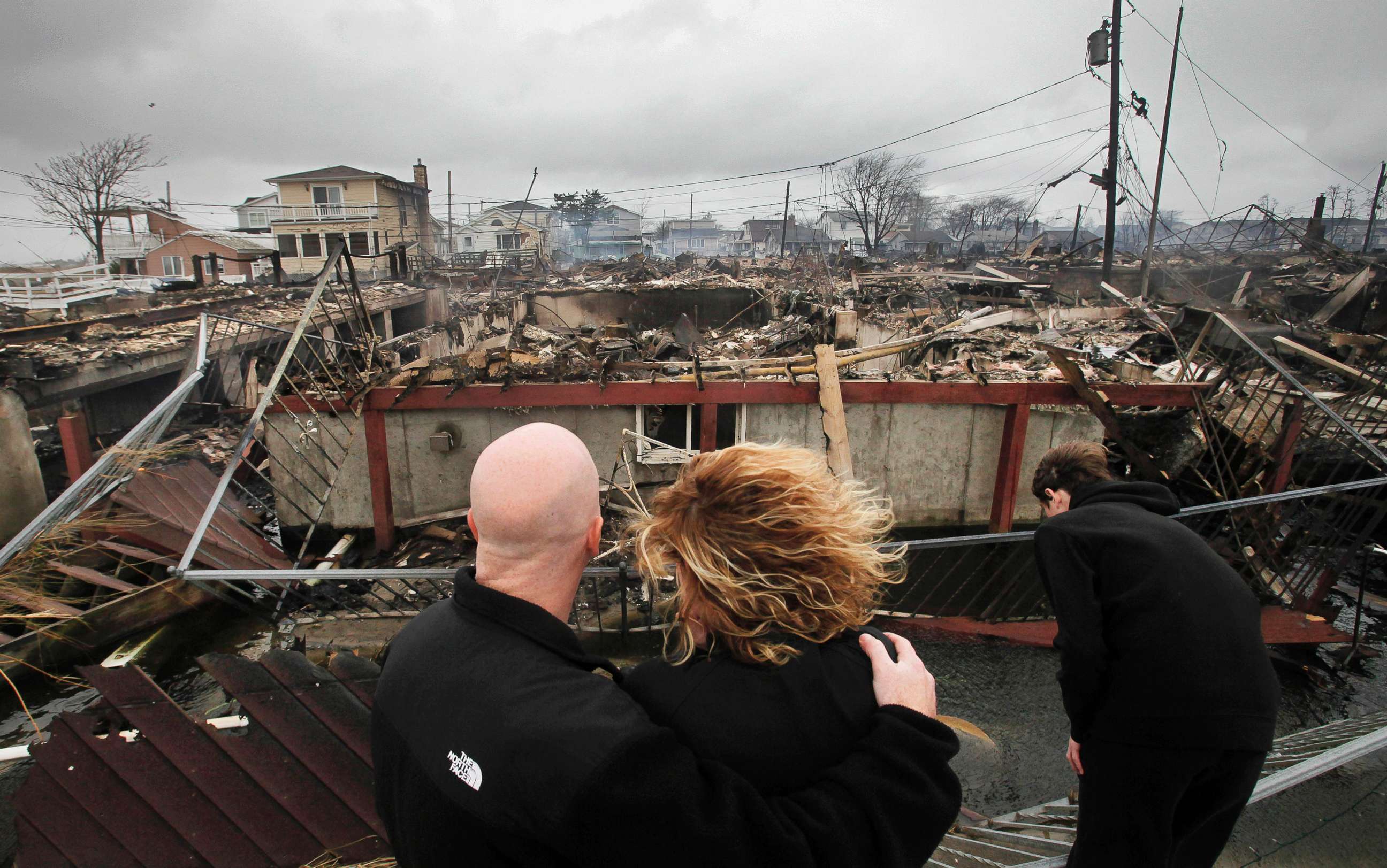 PHOTO: Robert Connolly, left, embraces his wife Laura as they survey the remains of the home owned by her parents that burned to the ground during Superstorm Sandy in the Breezy Point section of New York, Oct. 30, 2012. 
