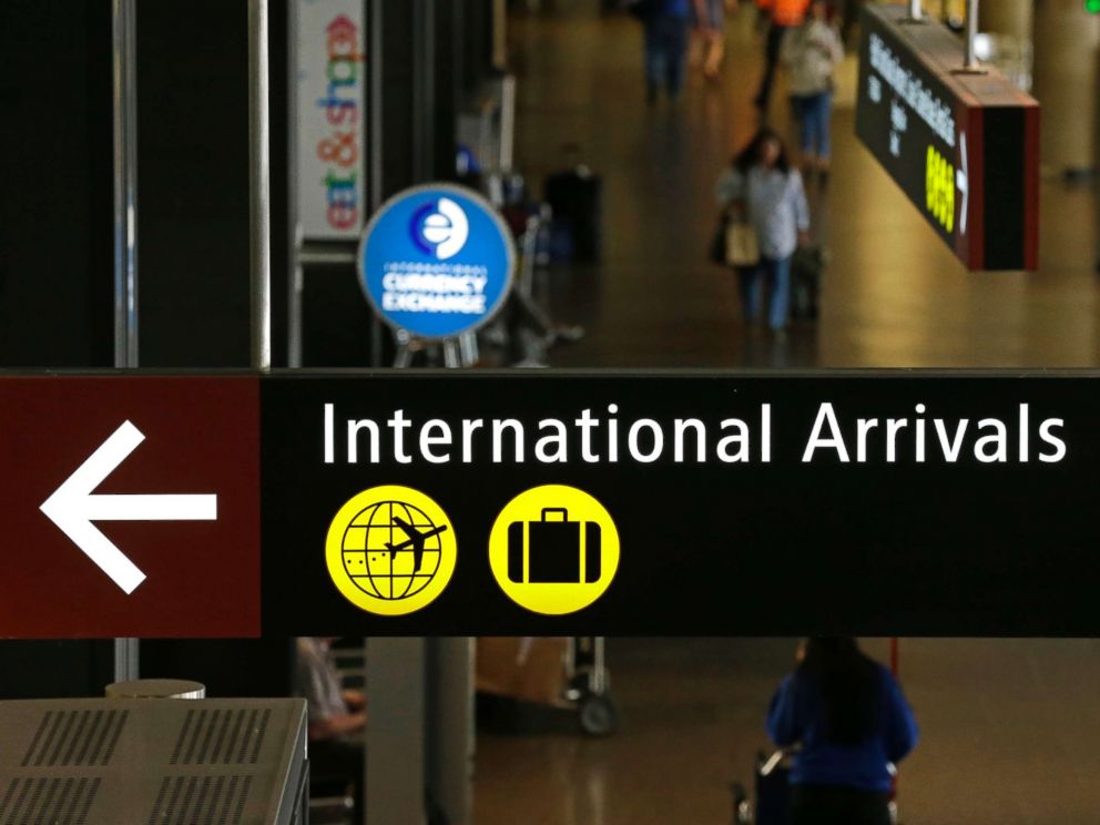 PHOTO: Travelers walk near a sign for international arrivals at the Seattle-Tacoma International Airport, June 26, 2017, in Seattle.