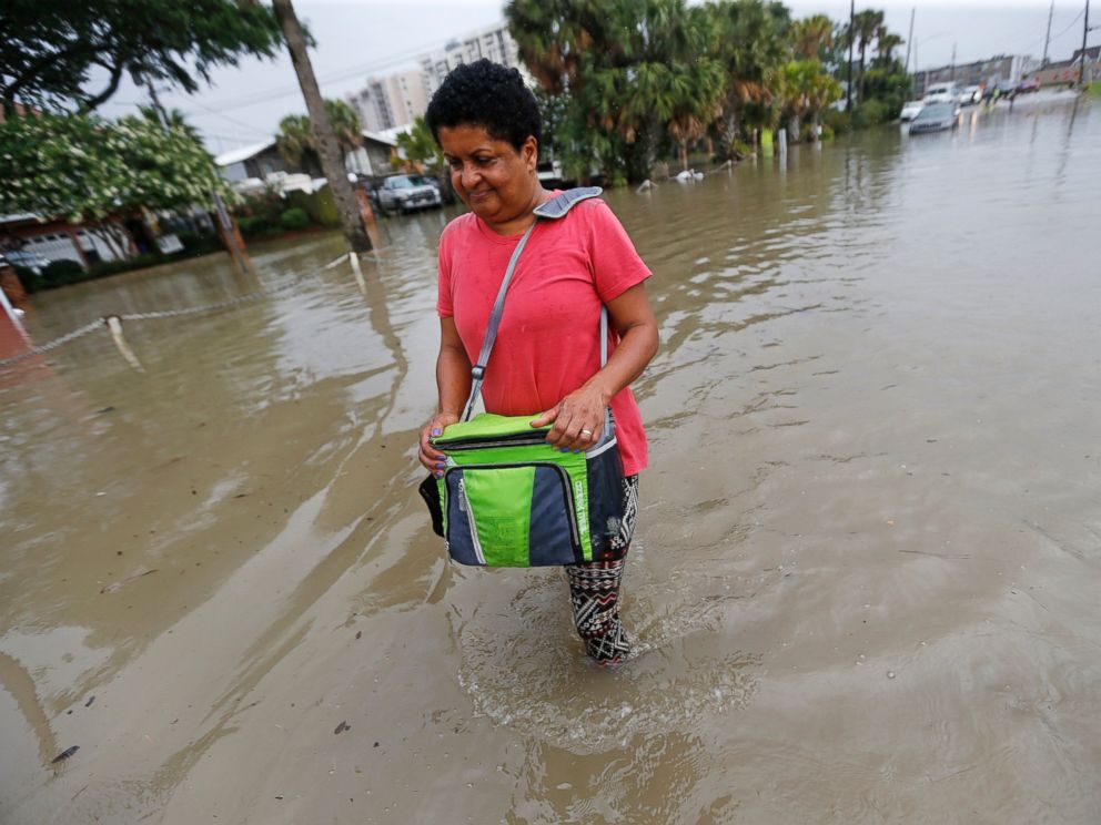 PHOTO: Esther Martens walk through a flooded roadway to get to her car in the West End section of New Orleans, June 21, 2017.