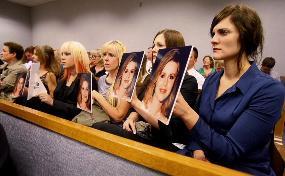 PHOTO: Family members hold up photos of Michele MacNeill facing Martin MacNeill as he enters the courtroom in Provo, Utah, Aug. 27, 2012.