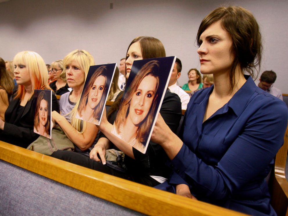 PHOTO: Family members hold up photos of Michele MacNeill facing Martin MacNeill as he enters the courtroom in Provo, Utah, Aug. 27, 2012.