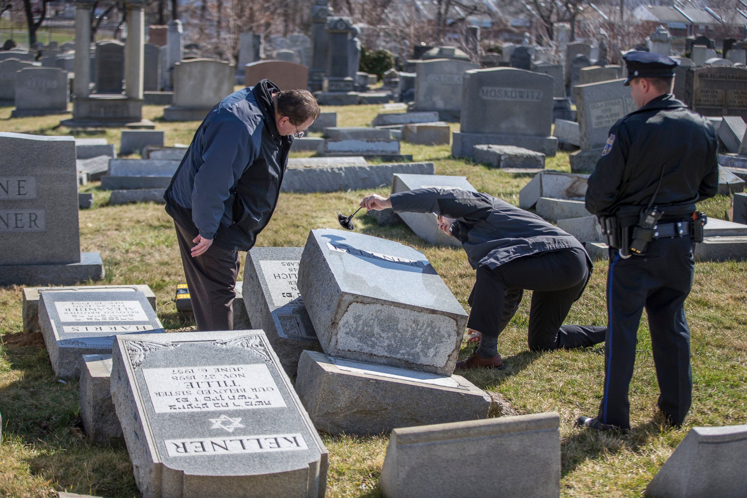 PHOTO: Northeast Philadelphia Police Detective Timothy McIntyre, center, dusts for fingerprints one of the headstones that were knocked down as Detective Nick McReynolds, left, looks on at Mount Carmel Cemetery in Philadelphia, Feb. 26, 2017. 