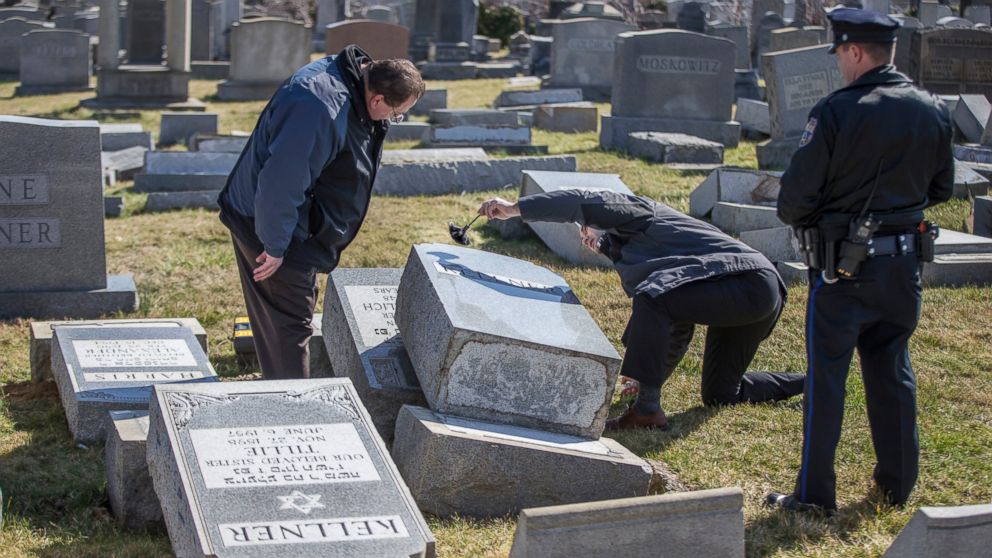 PHOTO: Northeast Philadelphia Police Detective Timothy McIntyre, center, dusts for fingerprints one of the headstones that were knocked down as Detective Nick McReynolds, left, looks on at Mount Carmel Cemetery in Philadelphia, Feb. 26, 2017. 
