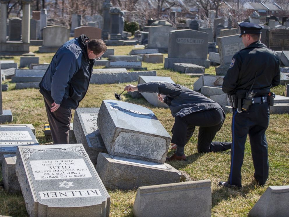 PHOTO: Northeast Philadelphia Police Detective Timothy McIntyre, center, dusts for fingerprints one of the headstones that were knocked down as Detective Nick McReynolds, left, looks on at Mount Carmel Cemetery in Philadelphia, Feb. 26, 2017.