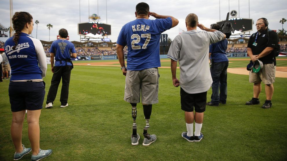 U.S. Army veteran Wesley Barrientos, center, who lost his legs in 2007 while serving in Iraq, listens to the national anthem before a baseball game between the Los Angeles Dodgers and the Arizona Diamondbacks, June 9, 2015, in Los Angeles.