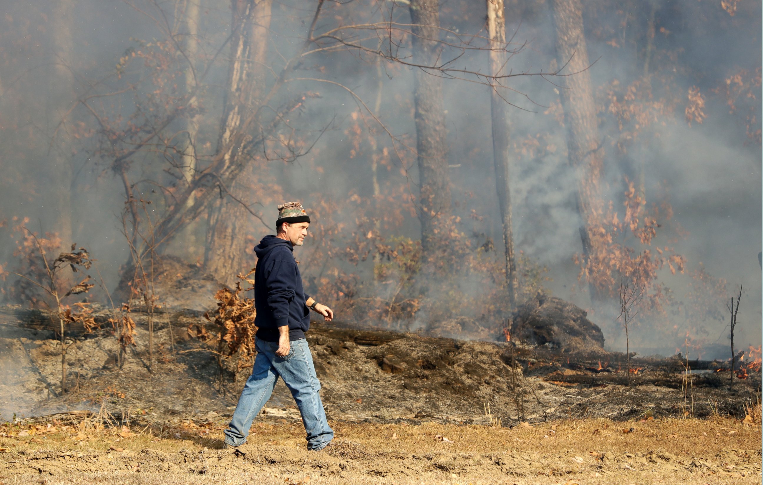 PHOTO: David Benton walks past burning trees and brush at his home, Nov. 10, 2016, in Soddy-Daisy, Tennessee.