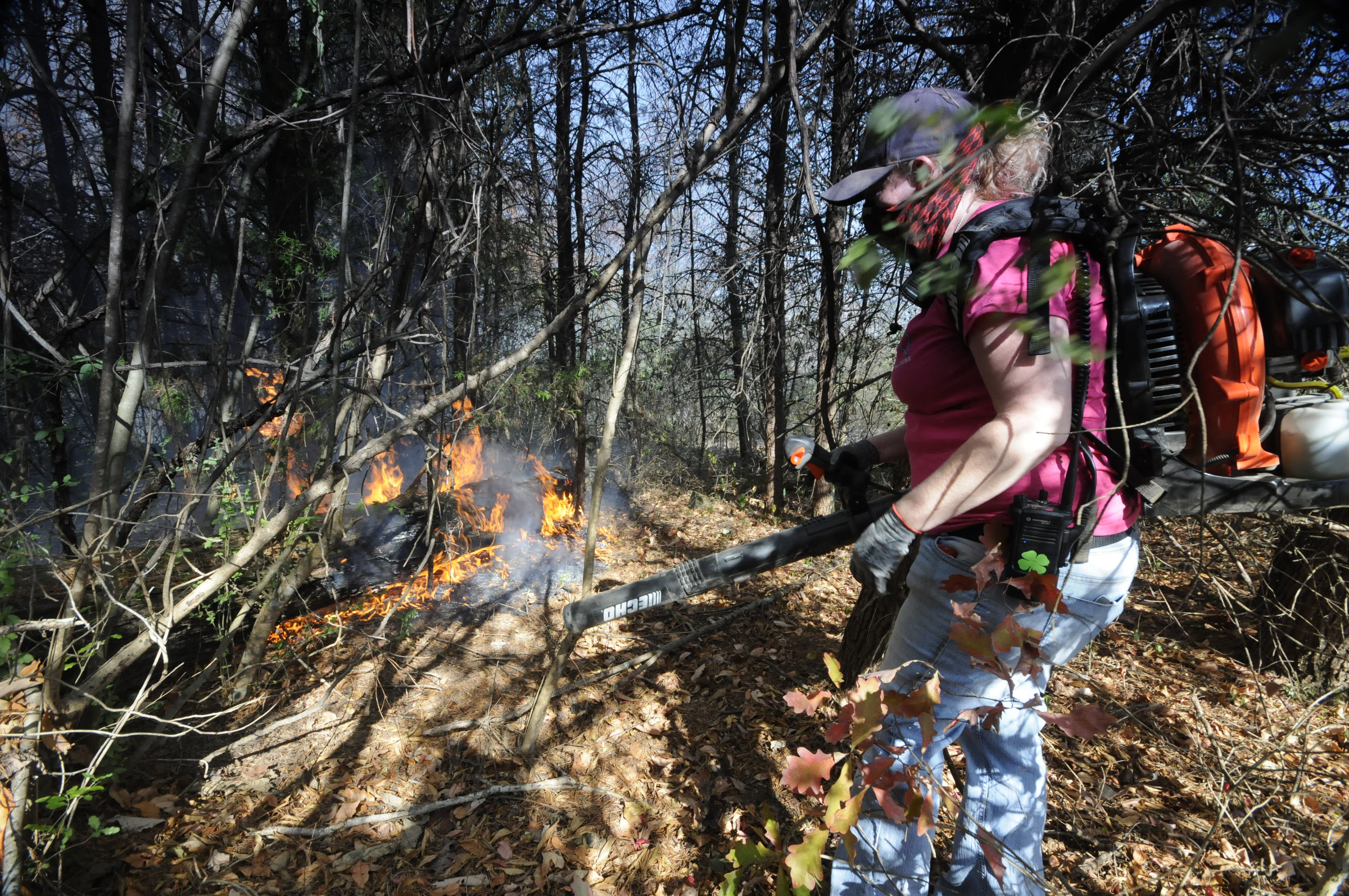 PHOTO: Volunteer firefighter's Sheri Torbett, with the Sequoyah Volunteer Fire Department, uses a leaf blower to turn back approaching flames near the Mowbray Volunteer Fire Hall in Soddy-Daisy, Tennessee. 