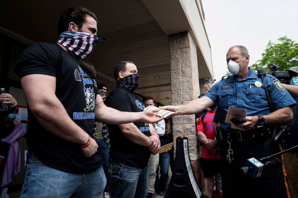 PHOTO: A police officer issues Atilis Gym co-owners Ian Smith, left, and Frank Trumbetti summons outside their gym in Bellmawr, N.J., Monday, May 18, 2020. The New Jersey gym reopened for business early Monday, defying a state order.