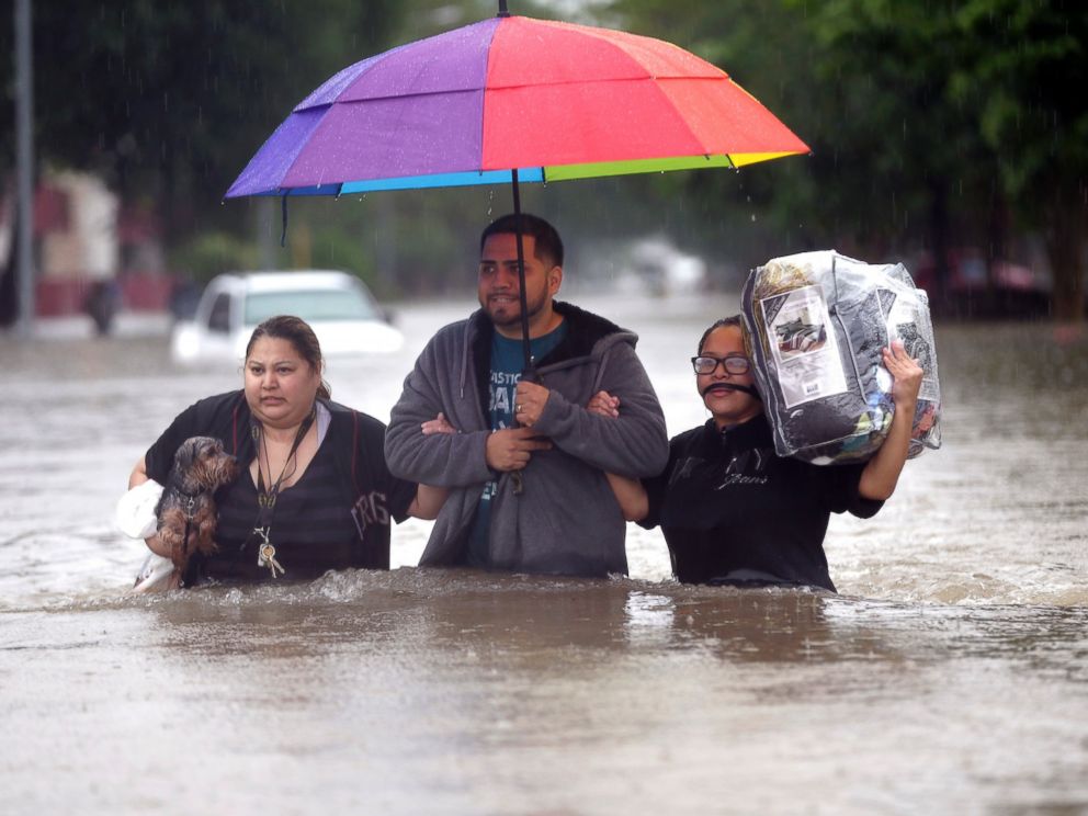 PHOTO: Felix Yanez, center, helps Lucy Olvio, right, and Judy wade through floodwaters as they evacuate from their flooded apartment complex, April 18, 2016, in Houston.