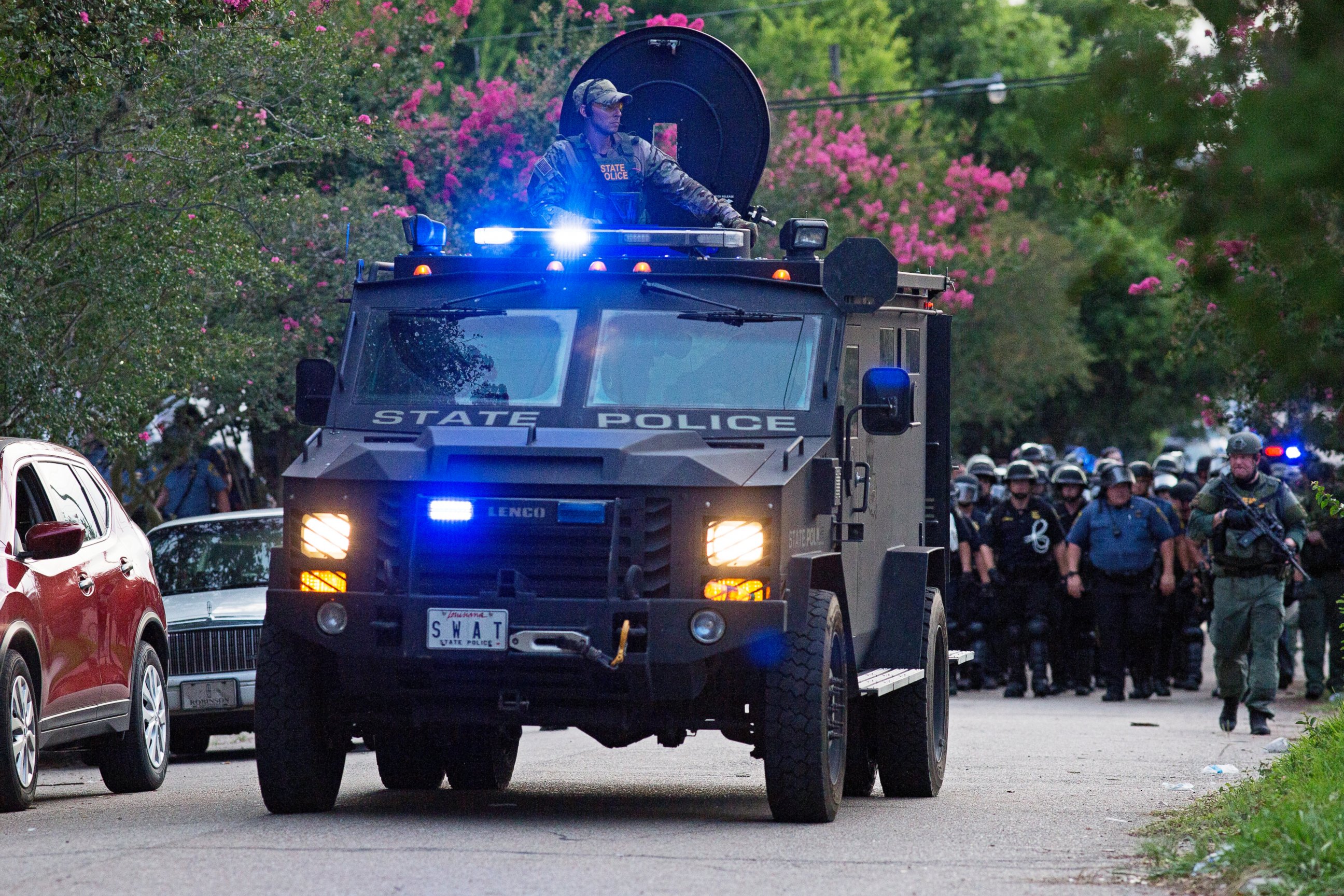 PHOTO: An armored police truck leads a troop of police through a residential neighborhood in Baton Rouge, Louisiana on July 10, 2016. 