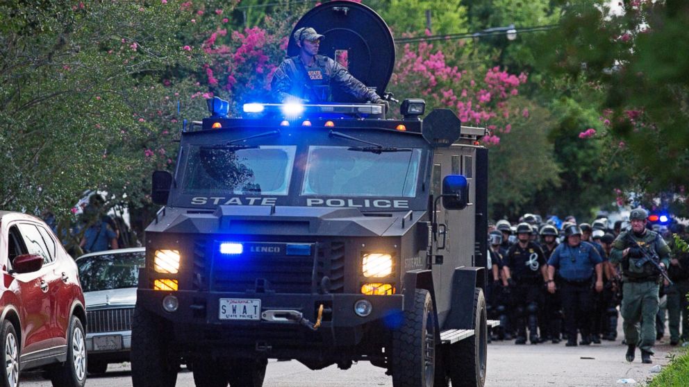 PHOTO: An armored police truck leads a troop of police through a residential neighborhood in Baton Rouge, Louisiana on July 10, 2016.