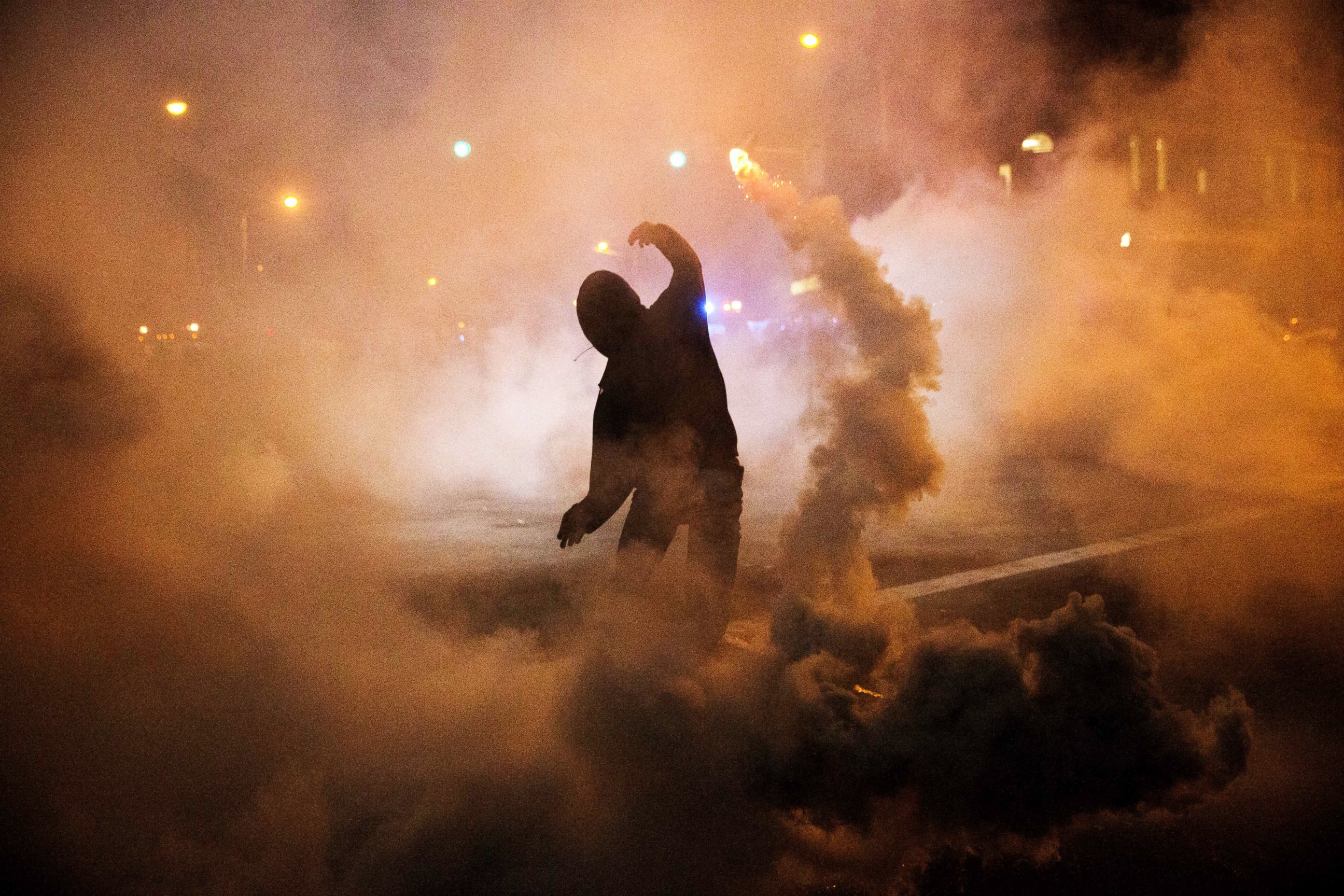 PHOTO: A protester throws a tear gas canister back toward riot police after a 10 p.m. curfew went into effect, April 28, 2015, in Baltimore.