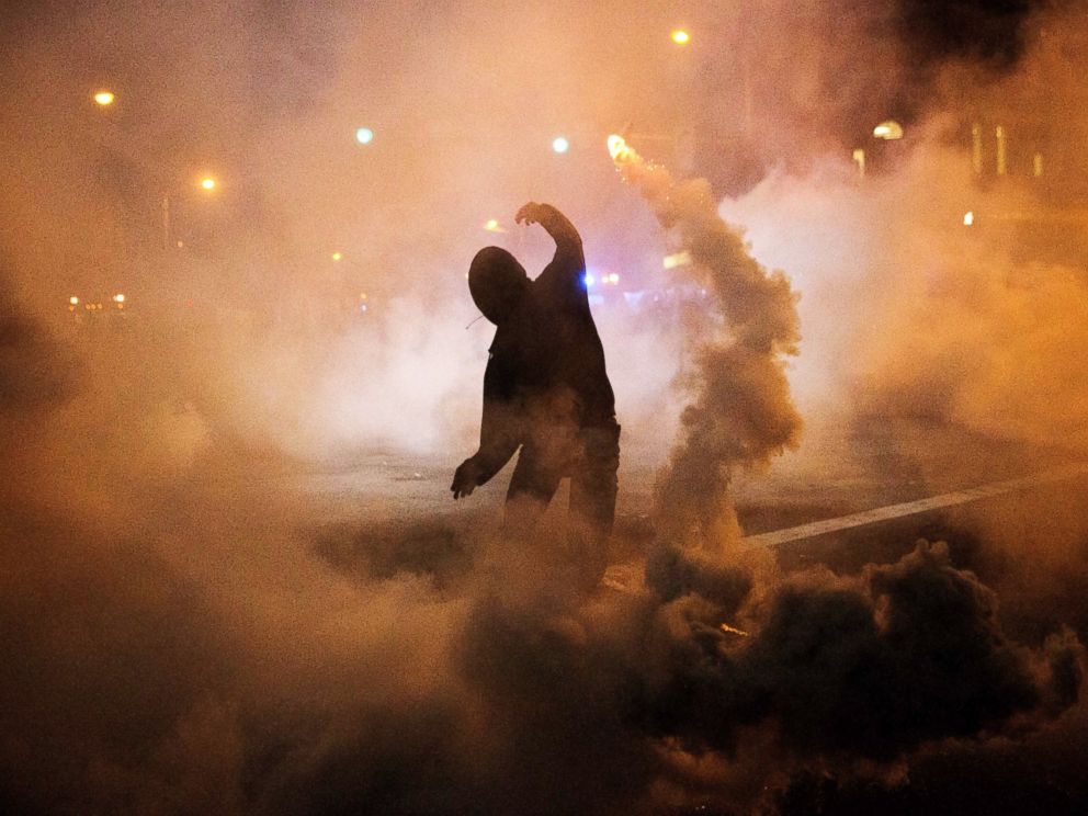 PHOTO: A protester throws a tear gas canister back toward riot police after a 10 p.m. curfew went into effect, April 28, 2015, in Baltimore.