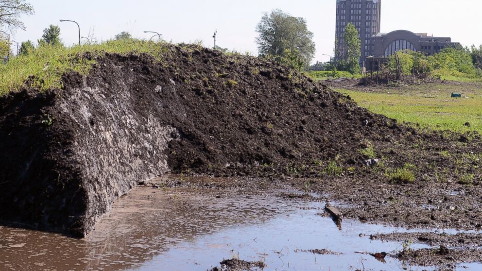 A dirt covered snow pack, dumped eight months ago, creates pools of water as it slowly melts around the abandoned train station vacant lot,  July 28, 2015, in Buffalo, N.Y.