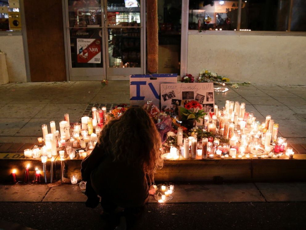 PHOTO: A woman places a candle in front of IV Deli Mart in Isla Vista, Calif., May 24, 2014, following a mass shooting one day earlier.