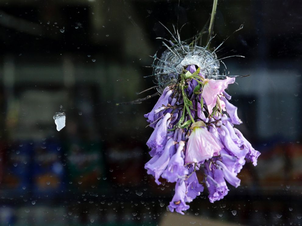 PHOTO: Flowers hang through a bullet hole on a window of IV Deli Mart following a mass shooting in Isla Vista, Calif., May 24, 2014.