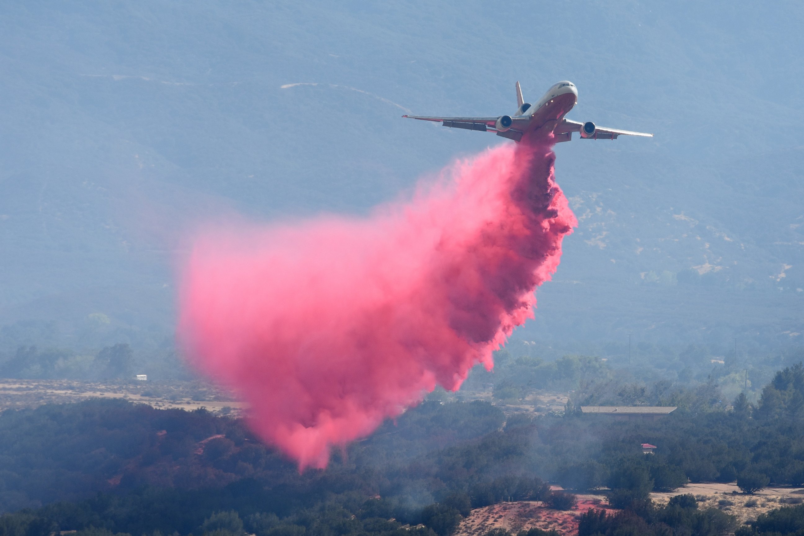 PHOTO: A DC-10 air tanker sprays fire retardant near homes in Hesperia, California, near a wildfire on Aug. 7, 2016. 
