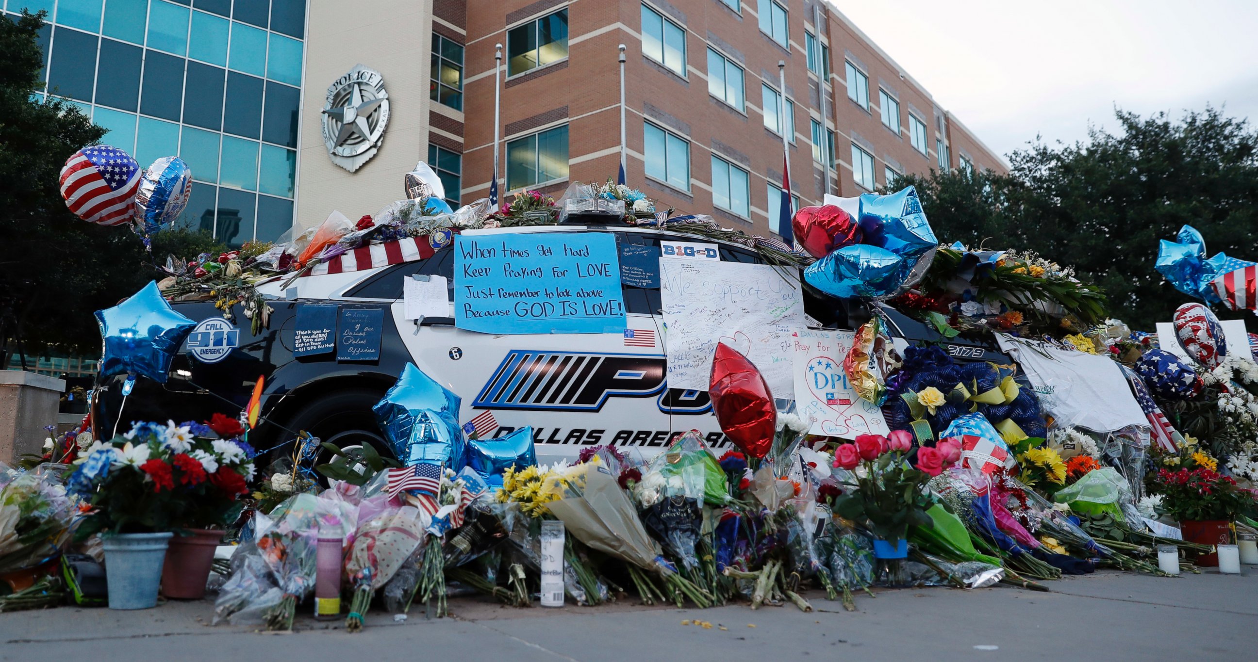 PHOTO: Two Dallas police patrol cars are covered with notes, flowers, balloons and other items as part of a makeshift memorial at the headquarters, July 10, 2016, in Dallas. 