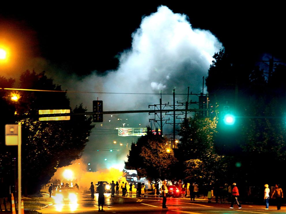 PHOTO: Police officers work their way north on West Florissant Avenue in Ferguson, Mo., clearing the road with the use of tear gas and smoke bombs, Aug. 13, 2014.