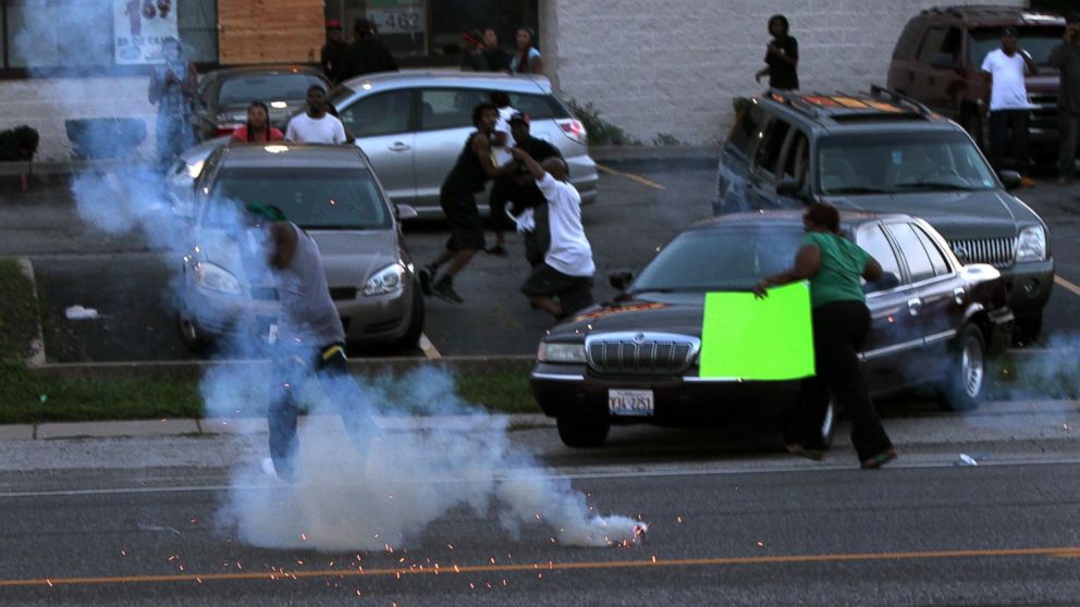 PHOTO: People scatter as police officers fire tear gas, Aug. 11, 2014, in Ferguson, Mo.