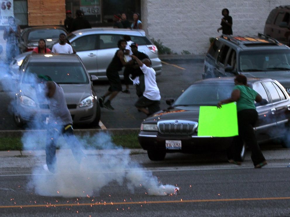PHOTO: People scatter as police officers fire tear gas, Aug. 11, 2014, in Ferguson, Mo.