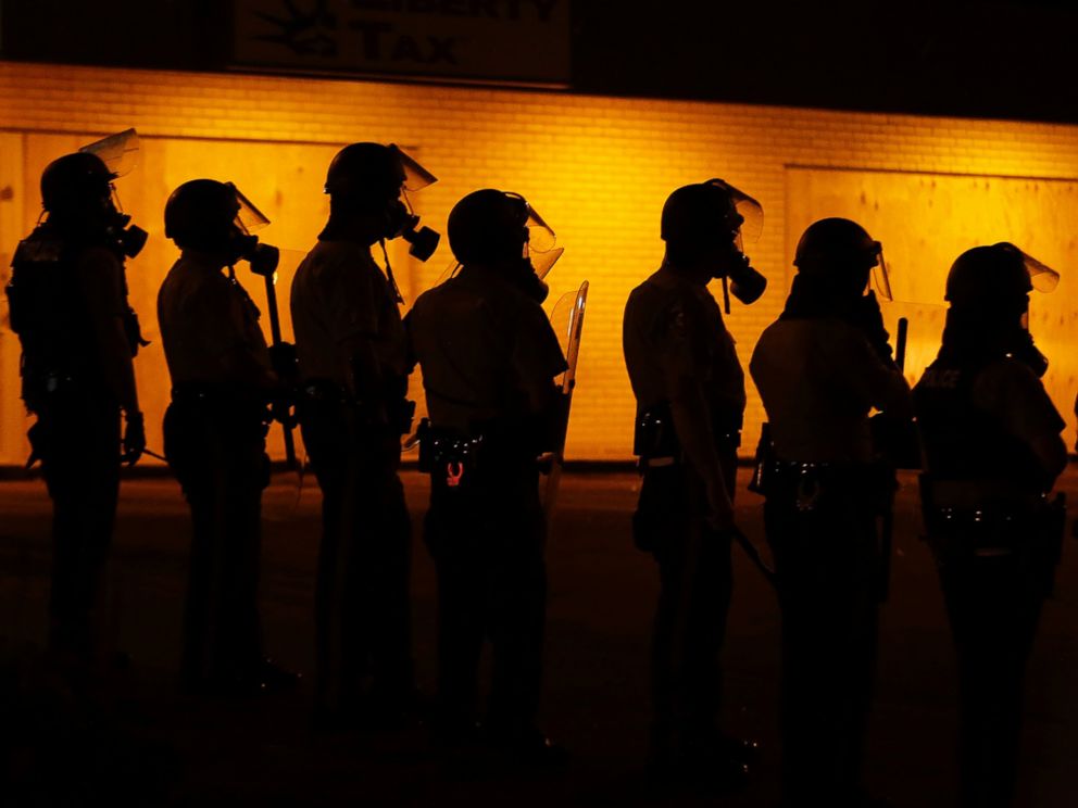 PHOTO: Police wait to advance after tear gas was used to disperse a crowd in Ferguson, Mo., Aug. 17, 2014.