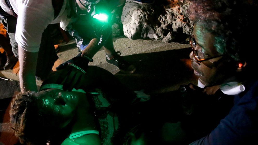 PHOTO: People help a woman sprayed with chemicals after police attempted to disperse a protest in Ferguson, Mo., Aug. 20, 2014.