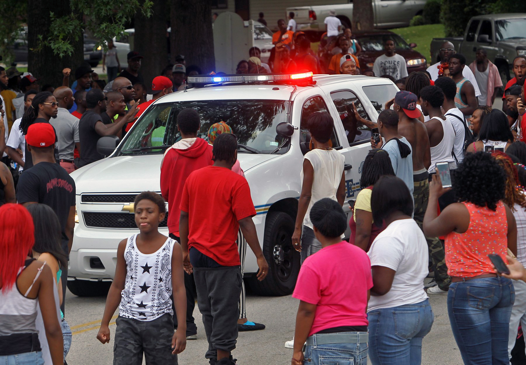 PHOTO: Protesters bang on the side of a police car, Aug. 10, 2014, in Ferguson, Mo.