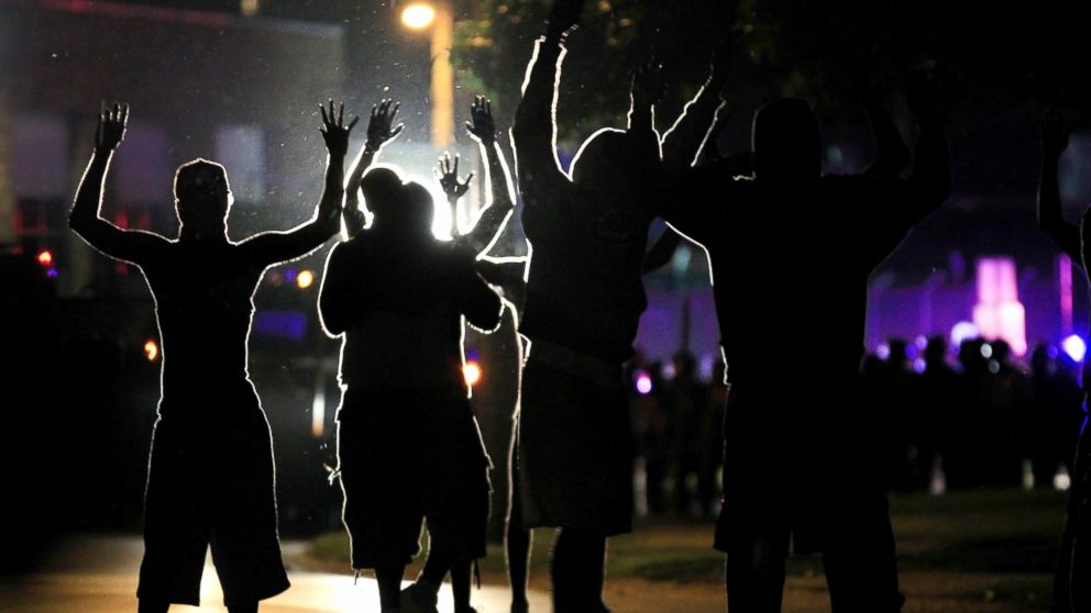 PHOTO: People raise their hands in the middle of the street as police wearing riot gear move toward their position trying to get them to disperse, Aug. 11, 2014, in Ferguson, Mo.