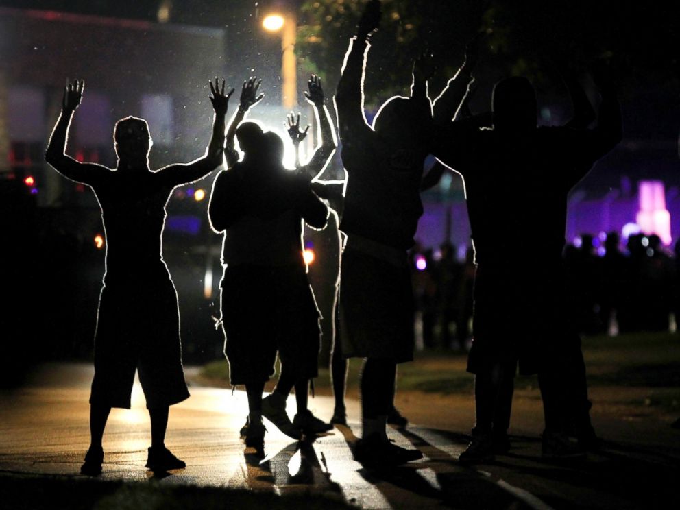 PHOTO: People raise their hands in the middle of the street as police wearing riot gear move toward their position trying to get them to disperse, Aug. 11, 2014, in Ferguson, Mo.