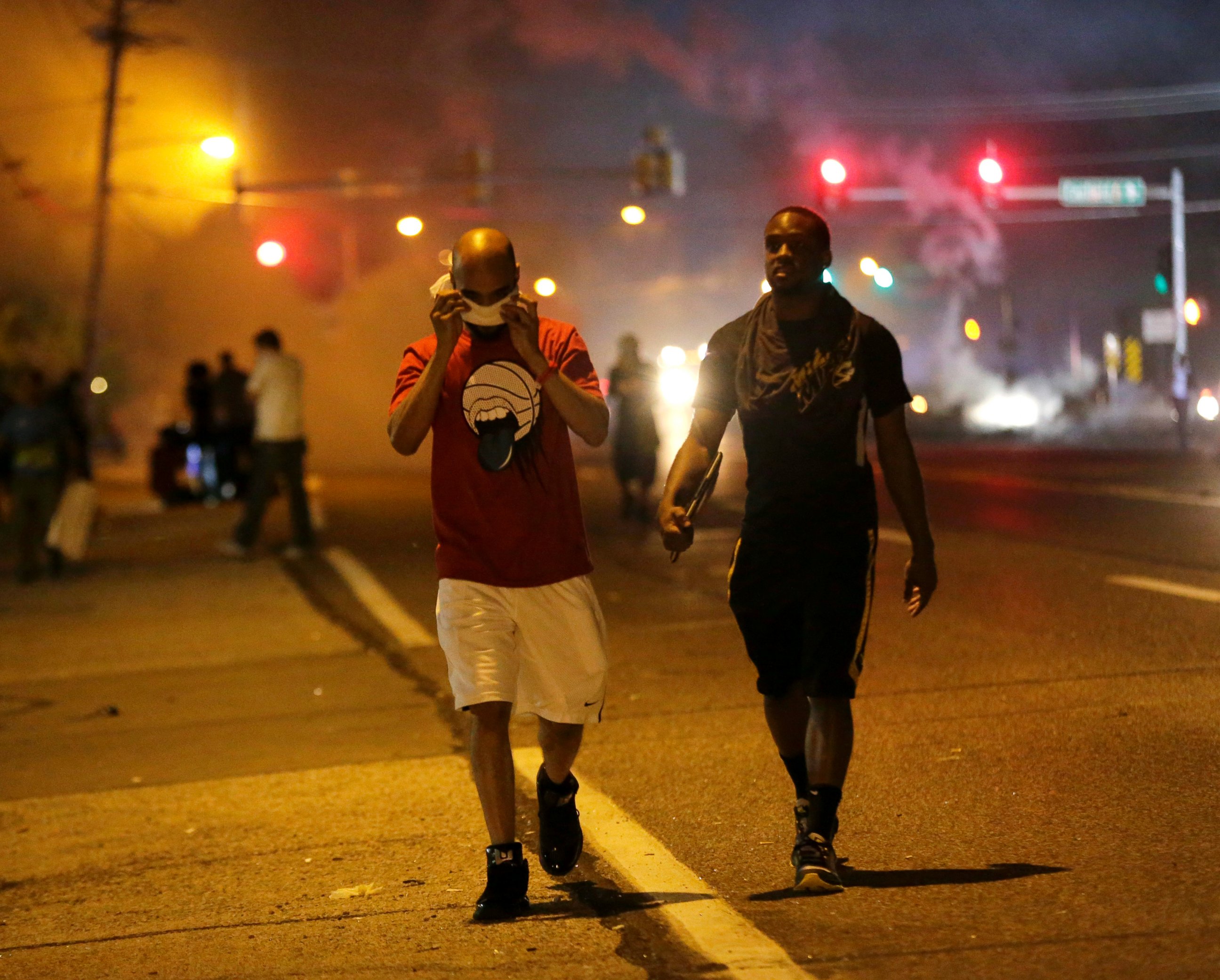 PHOTO: Men walk away from a cloud of tear gas during a protest, Aug. 18, 2014, in Ferguson, Mo.