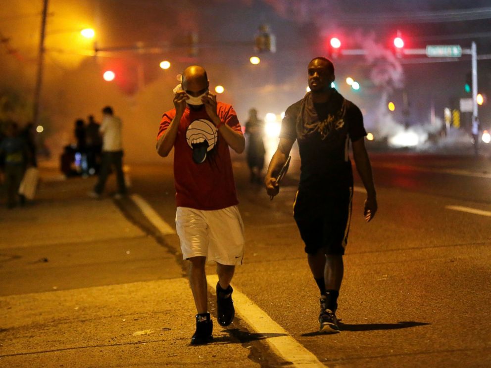 PHOTO: Men walk away from a cloud of tear gas during a protest, Aug. 18, 2014, in Ferguson, Mo.