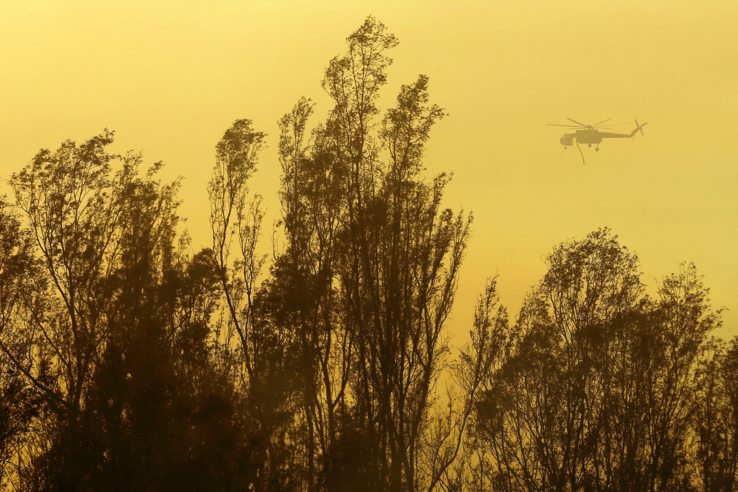 PHOTO: A helicopter transporting water flies over trees, May 15, 2014, in Escondido, Calif.