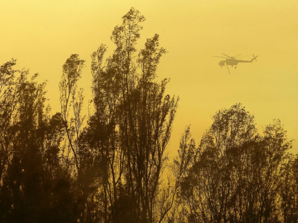 PHOTO: A helicopter transporting water flies over trees, May 15, 2014, in Escondido, Calif.